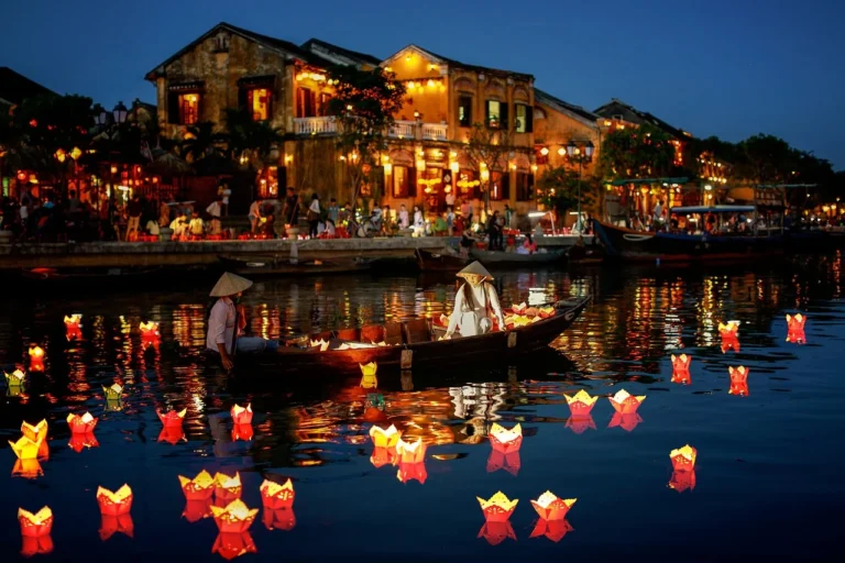 Vietnamese locals in traditional hats floating lanterns on Hoi An river, celebrating sustainability with Zero Plastic Waste Journey